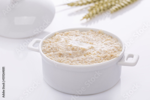 Oat porridge in a white saucepan. Oatmeal. Cap.