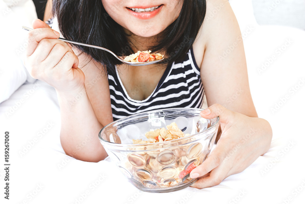 Woman eating cornflakes cereals in the bed in the morning Woman eating cornflakes cereals in the bed in the morning