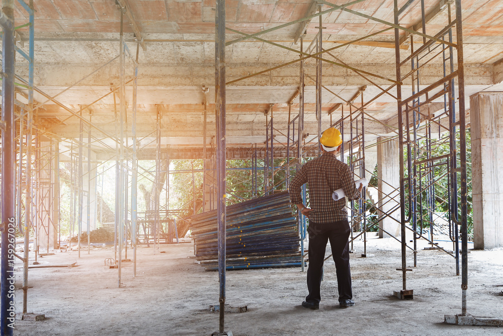 Engineer with blueprint in building construction site Engineer with blueprint in building construction site
