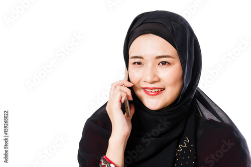 Beautiful young muslim woman using moblie phone on a white background.