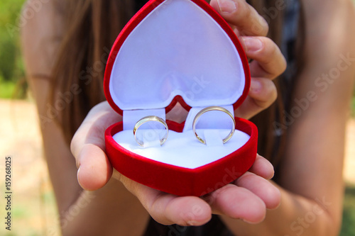 women hands with a velvet red box with a pair of gold wedding rings