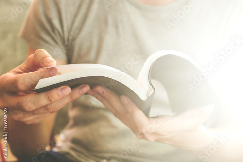 Close up of male hands holding a book to read, Flare from the sunlight
