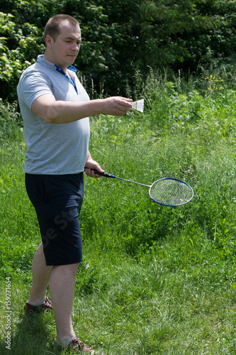 Young, handsome man start to play badminton in park - summer game