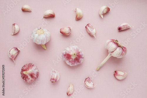Young pink garlic on a pink paper textured background. Pattern of garlic. Food background. Top view.