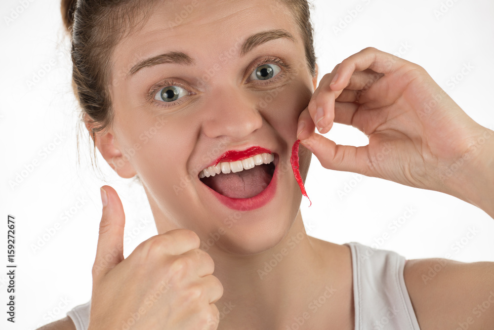 A beautiful young girl applies a persistent liquid red lipstick from a tube to her lips, and then takes it off as a film A beautiful young girl applies a persistent liquid red lipstick from a tube to her lips, and then takes it off as a film