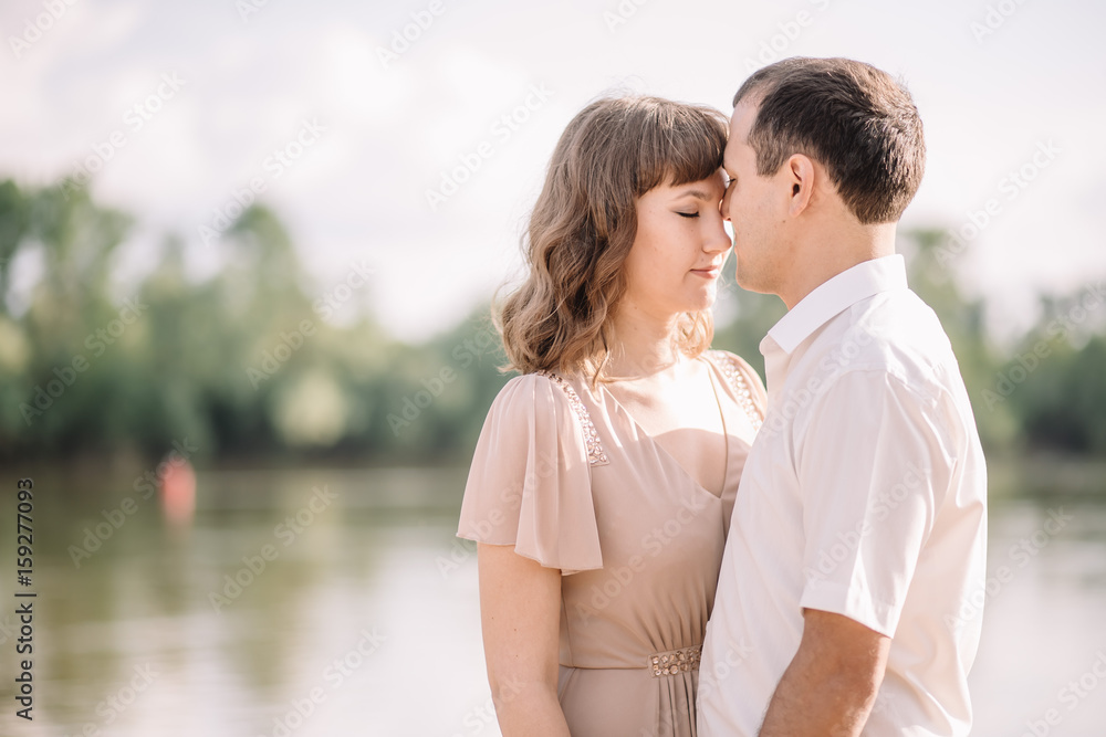 love story, beautiful couple a man and a woman in bright clothes, happy family, walking along the river Bank,are holding hands, cuddling, summer, nature love story, beautiful couple a man and a woman in bright clothes, happy family, walking along the river Bank,are holding hands, cuddling, summer, nature