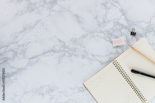 Creative mock-up flat lay of stationery on white marble texture background - Work space concept compose of notebook, post-it, pen, pencil, rubber, clip, scissors, calculator, and stapler