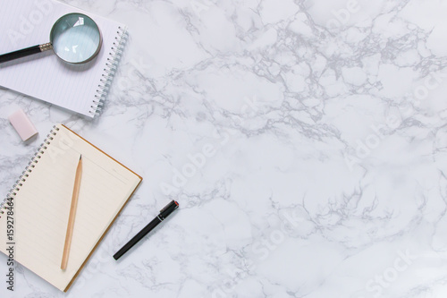 Creative mock-up flat lay of stationery on white marble texture background - Work space concept compose of notebook, post-it, pen, pencil, rubber, clip, scissors, calculator, and stapler