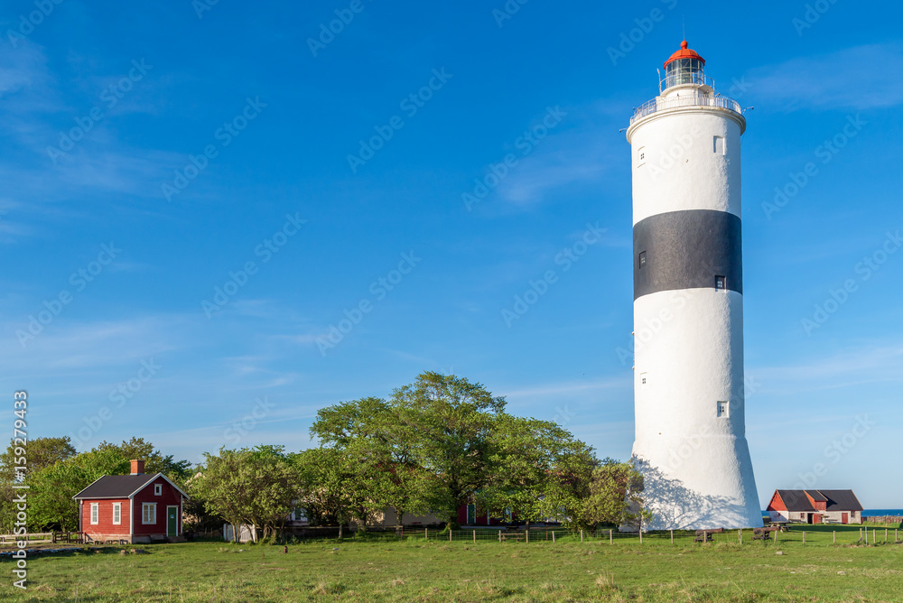 The tall lighthouse Long Jan on the island Oland in Sweden, seen with surrounding landscape and buildings on a fine sunny evening. The tall lighthouse Long Jan on the island Oland in Sweden, seen with surrounding landscape and buildings on a fine sunny evening.
