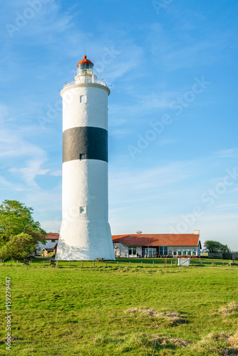 The tall lighthouse Long Jan on the island Oland in Sweden, seen with surrounding landscape and buildings on a fine sunny evening.