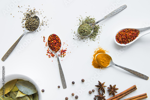 Fototapeta Naklejka Na Ścianę i Meble -  Top view of various dried aromatic spices in metal and ceramic spoons
