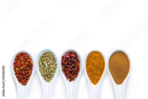 Top view of assorted aromatic spices in ceramic spoons isolated on white