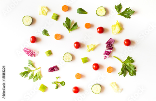 Eating pattern with raw ingredients of salad, lettuce leaves, cucumbers, red tomatoes, carrots, celery on white background