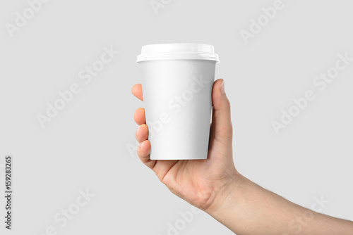 Canvas-taulu Mockup of male hand holding a Coffee paper cup isolated on light grey background