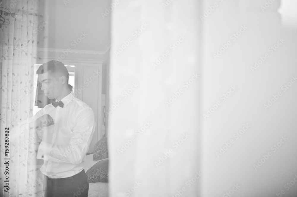 Handsome groom dressing up and getting ready for his wedding in the room. Handsome groom dressing up and getting ready for his wedding in the room.