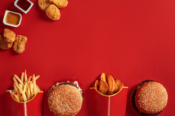 Burger and Chips. Hamburger and french fries in red paper box. Fast food on red background.