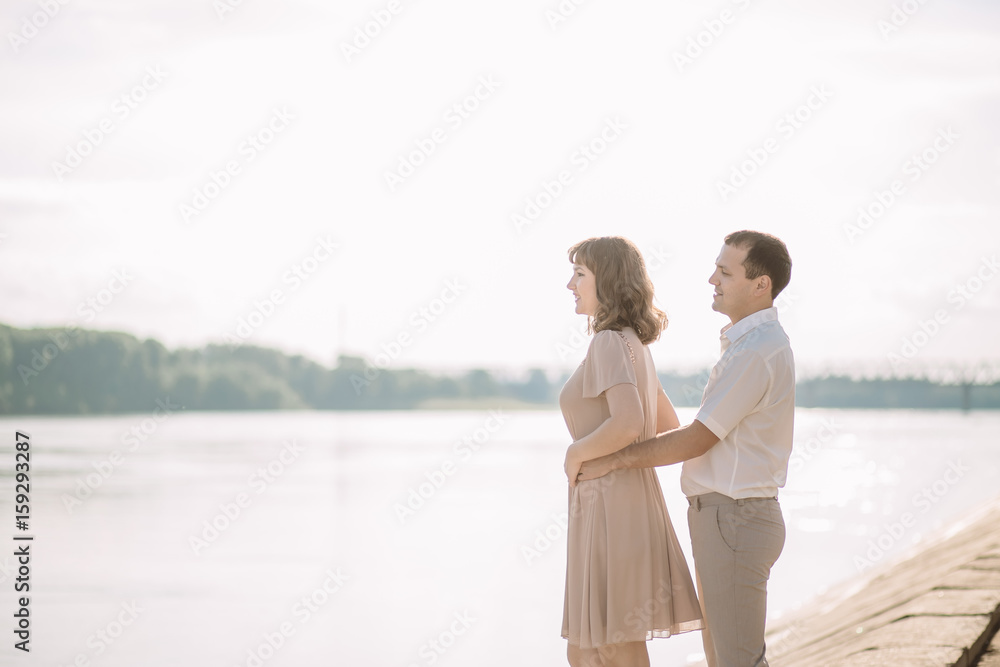beautiful couple man and woman in a light beige light clothing spend time together, enjoying each other, talking,cuddling standing on the river Bank, a happy family, a love story