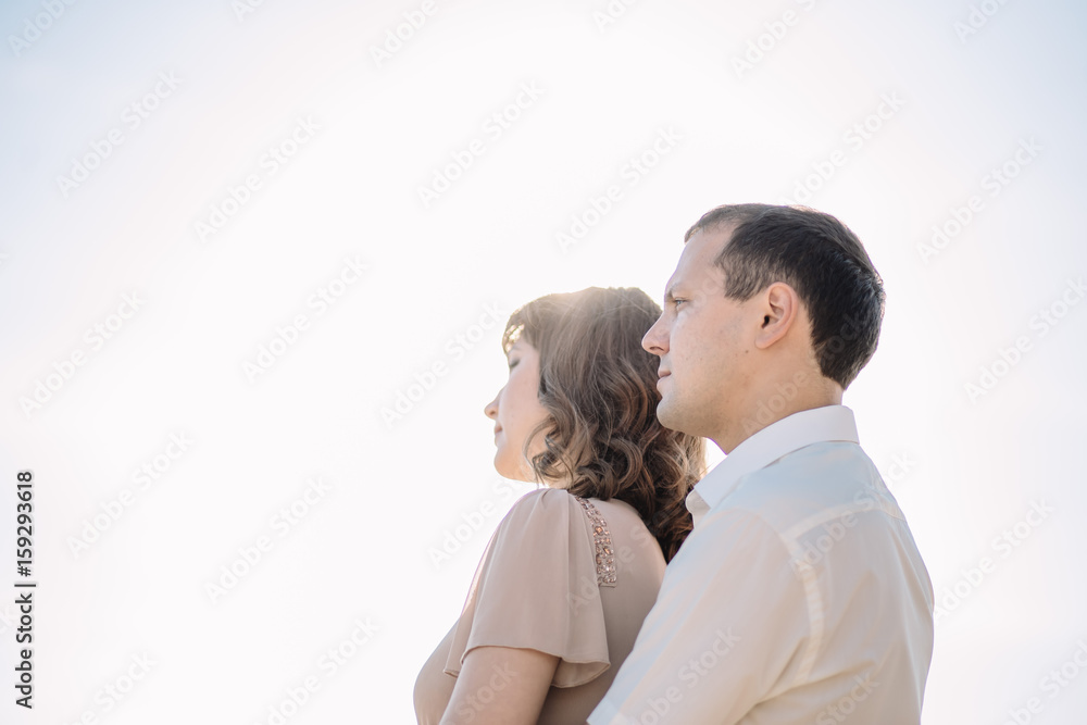 beautiful couple, the girl in the beige dress, the man in white shirt standing close to each other on the background of sky, sun, close-up, summer, heat, nature, love story beautiful couple, the girl in the beige dress, the man in white shirt standing close to each other on the background of sky, sun, close-up, summer, heat, nature, love story