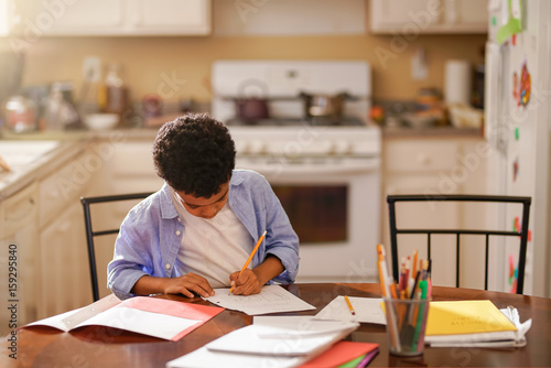 little boy in kitchen doing homework in the morning before school
