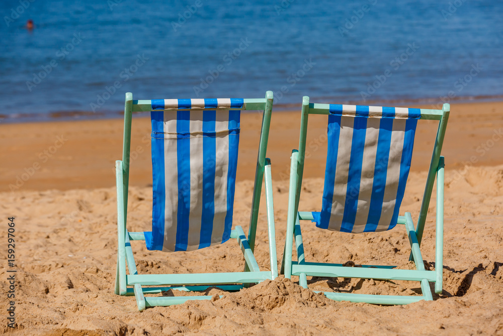 Two empty deckchairs facing the sea Two empty deckchairs facing the sea