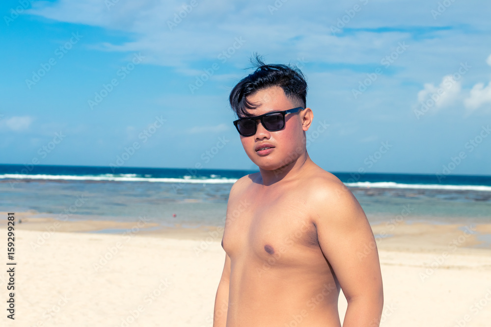 Young asian indonesian man on the beach of tropical Bali island, Indonesia.