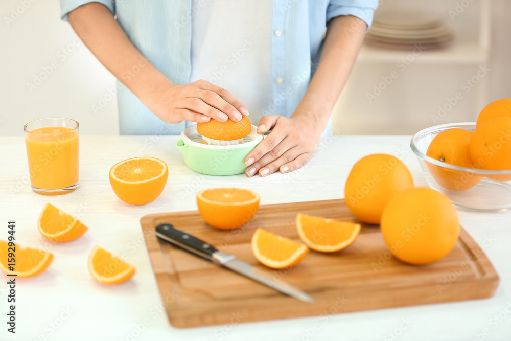 Female hands making orange juice on kitchen Female hands making orange juice on kitchen