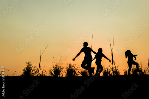 Running group of children running on meadow, sunset, silhouette
