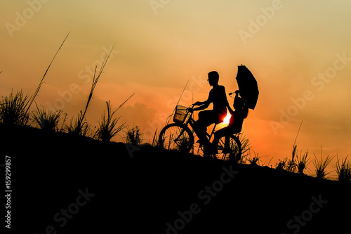 brother with sister riding bikes at sunset