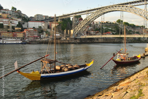 Barcos rabelos amarelo e azul parado no dio d'ouro no cais de Vila Nova de Gaia com a ponte Dom Luís de fundo