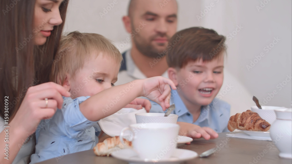 Happy young family of four having tea at restaurant or cafe or home Happy young family of four having tea at restaurant or cafe or home