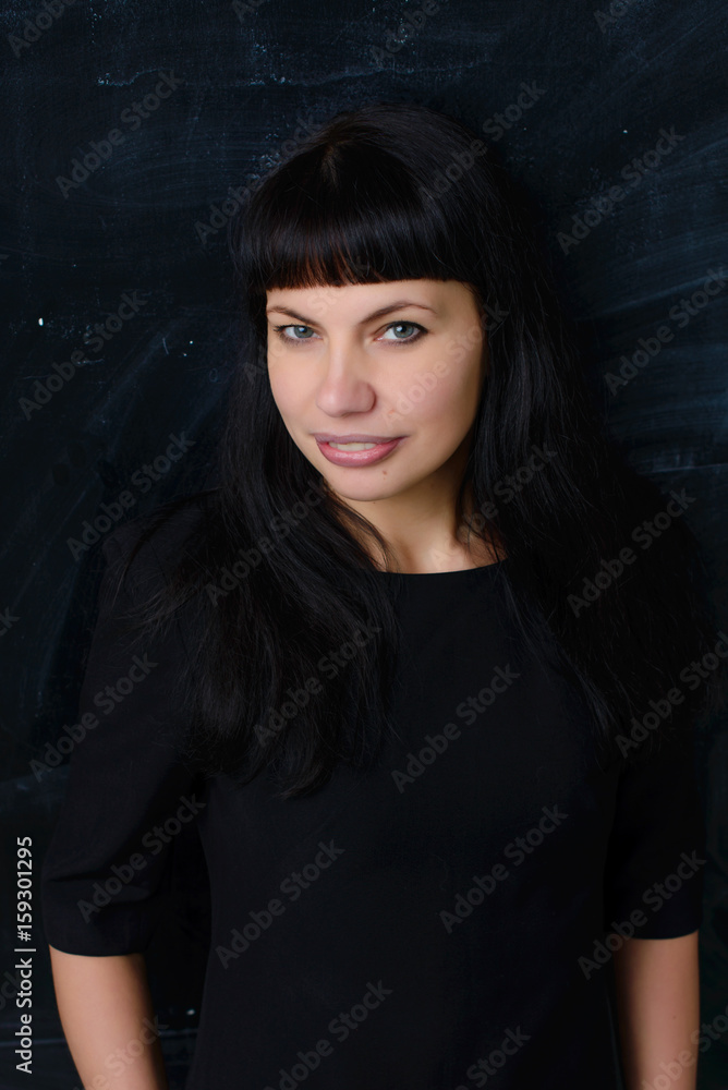 Confident business woman on a black background in a black dress