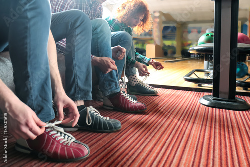 Friends lacing their shoes in bowling club
