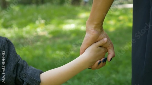 Closeup of child grabbing and holding mother hand