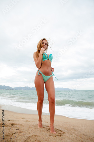 Attractive bikini female with long blond hair relaxing on the sea beach. Vietnam