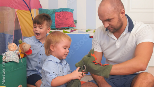 Happy parents and two little boys playing with puppets