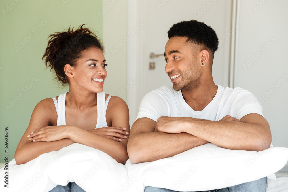 Smiling young african loving couple sitting on bed