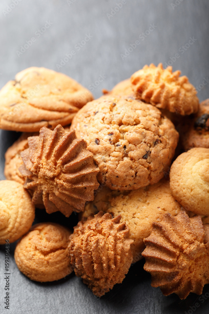 Assorted cookies with chocolate chip, oatmeal raisin on stone slate background on wooden background close up. Homemade baking. Top view, flat lay Assorted cookies with chocolate chip, oatmeal raisin on stone slate background on wooden background close up. Homemade baking. Top view, flat lay