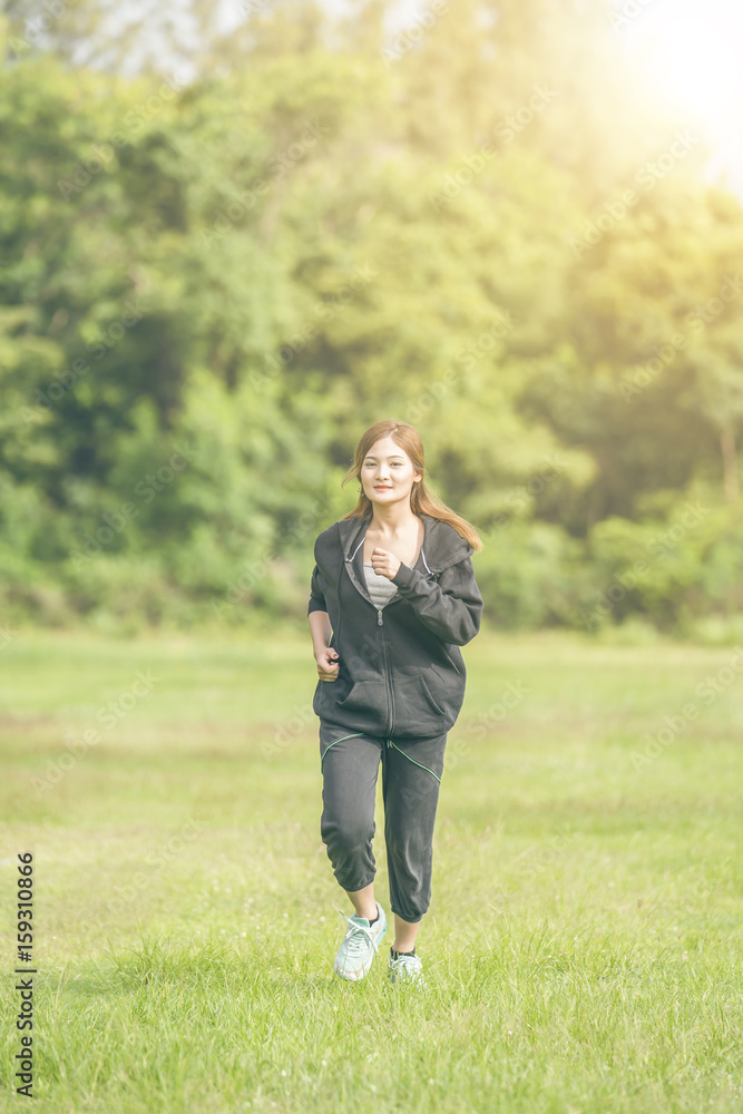 Pretty asian woman jogging at park in the morning fresh with sunrise..