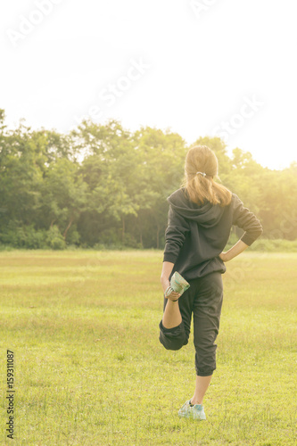 Portrait of fit and sporty young woman doing stretching in jungle trail in early morning..