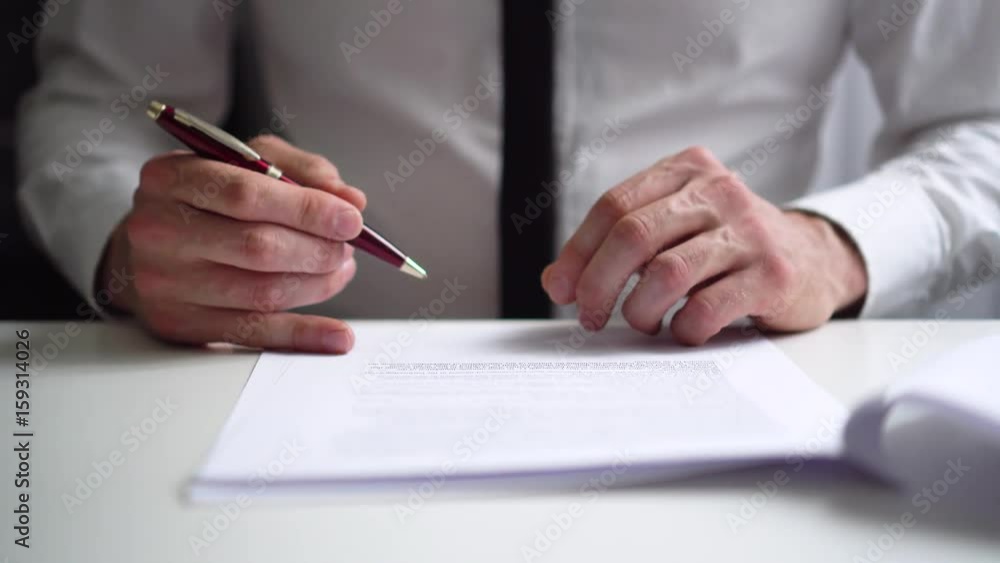 businessman reading and signing business partnership contract in office businessman reading and signing business partnership contract in office