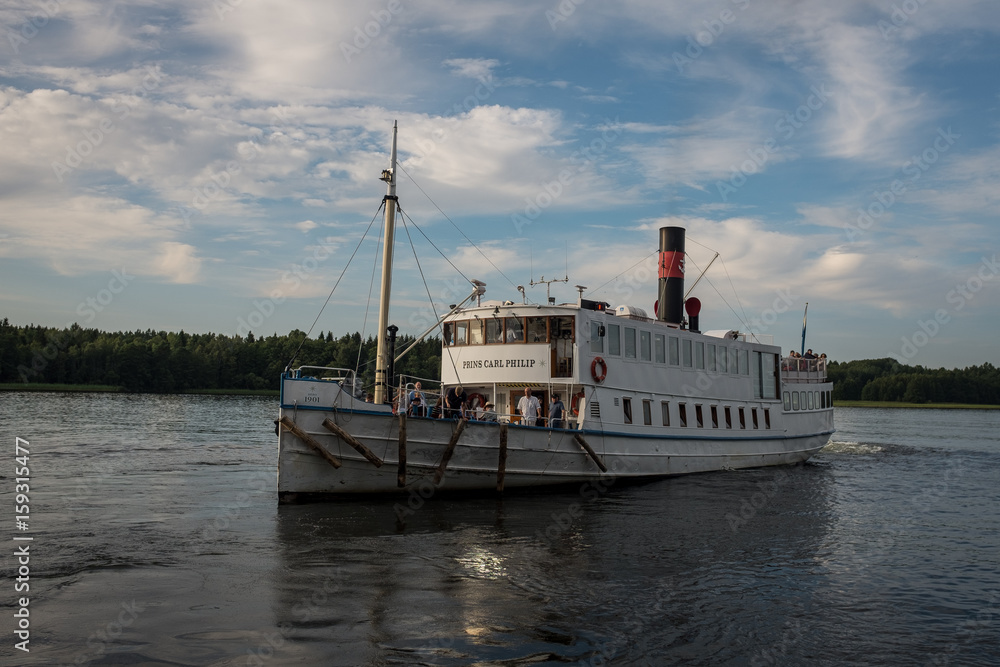 The white steam boat is about to add to one of the small islands in Stockholm archipelago, in the beautiful Swedish summer sunset
