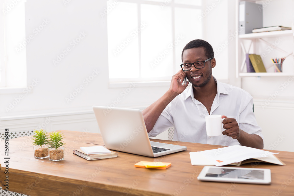 Young black businessman call mobile phone in modern white office
