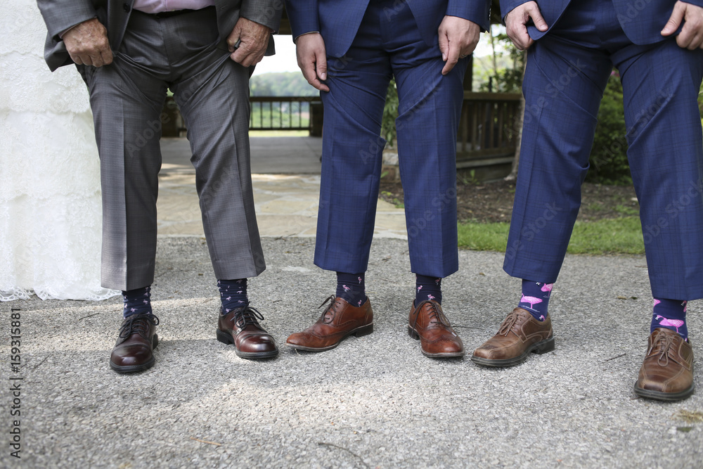 Groom and Groomsmen in Blue Suits Comparing Pink Flamingo Socks Groom and Groomsmen in Blue Suits Comparing Pink Flamingo Socks