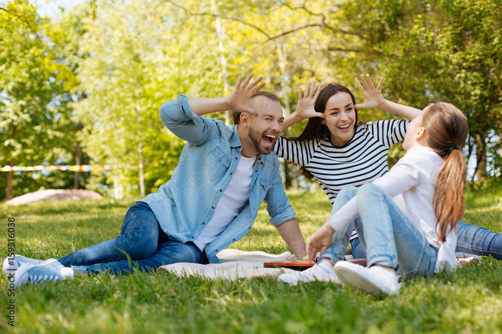 Fototapeta premium Joyful parents making faces for their daughter
