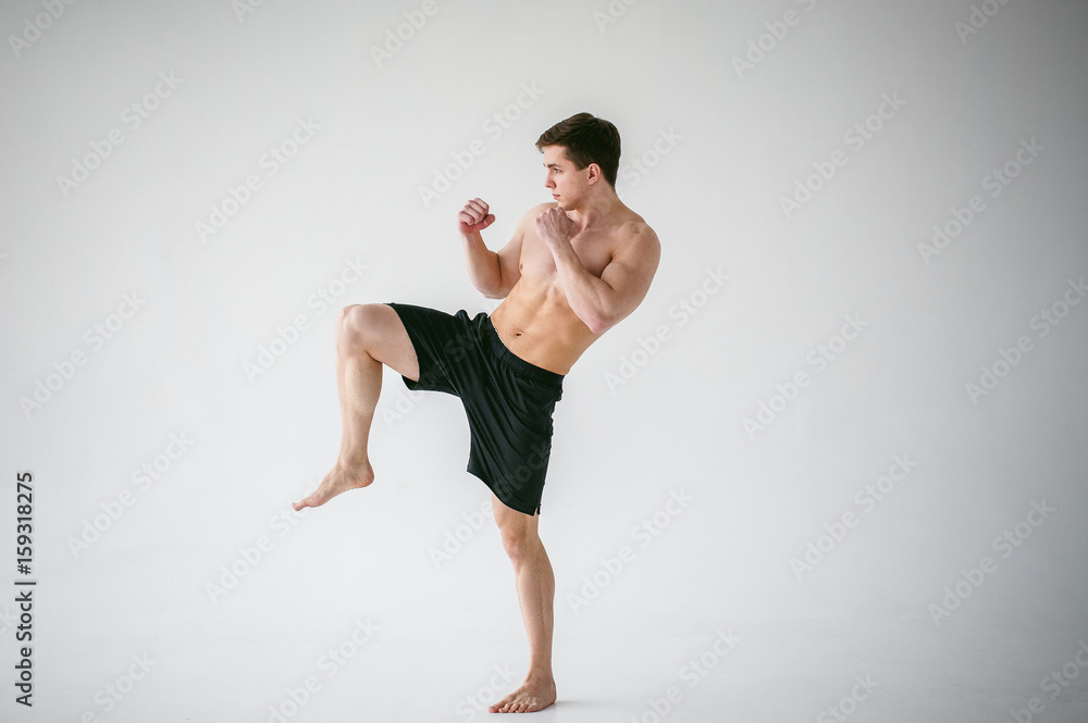 young sexy handsome men strong Athlete's body with bare torso, Dressed  black sports shorts, portrait of studio of light-skinned strong man  standing in fighting stance Kicking, straining powerful legs Stock Photo