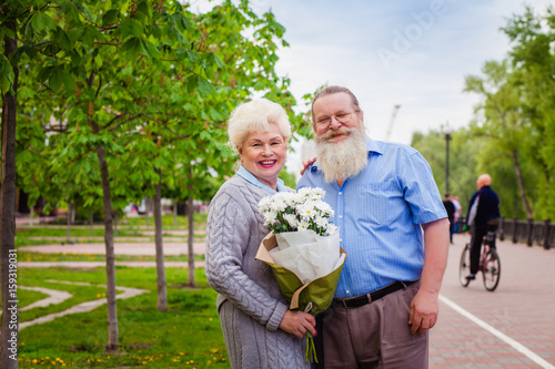 Attractive elderly couple walking around the city with a bouquet of flowers