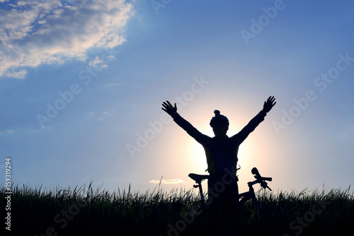 silhouette of a cyclist with a bike in the sun