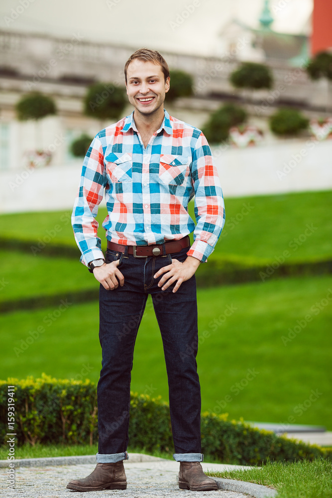 Portrait of happy young happy man posing near green lawn in park and looking  at camera. Trendy casual clothing, leather boots. Perfect smile. Warsaw,  Poland. Outdoor shot Stock Photo | Adobe Stock