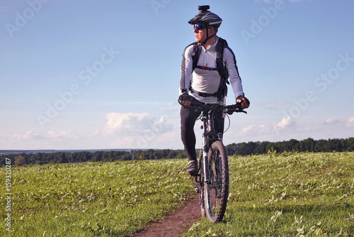 Fototapeta Naklejka Na Ścianę i Meble -  cyclist rides on the road in a field on a bright sunny day