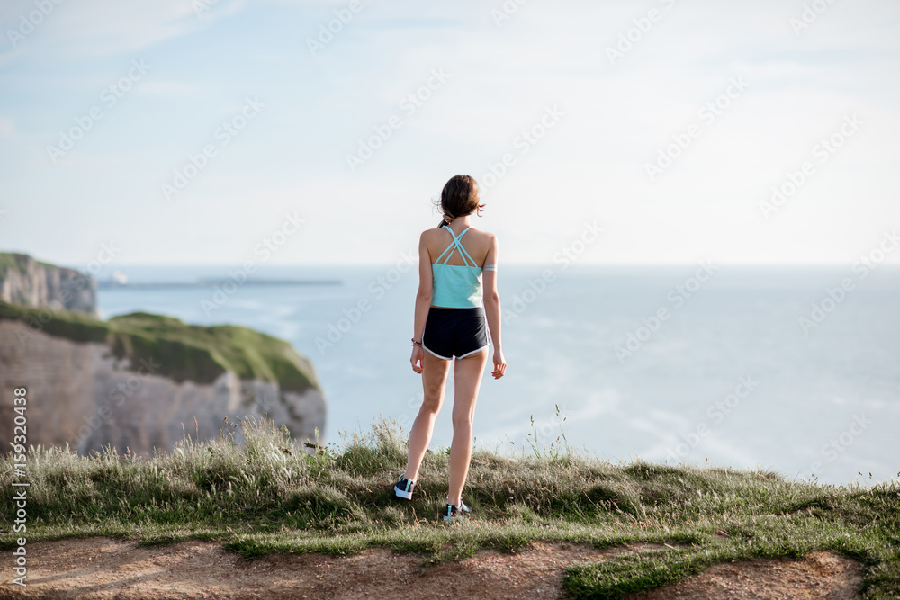 Young woman in sportswear enjoying great view on the rocky coastline near Etretat town in France